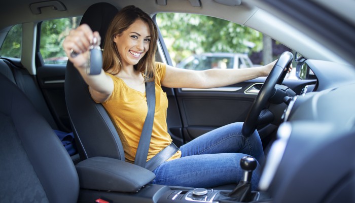 Beautiful female women driver sitting in her vehicle and holding car keys ready for a drive.