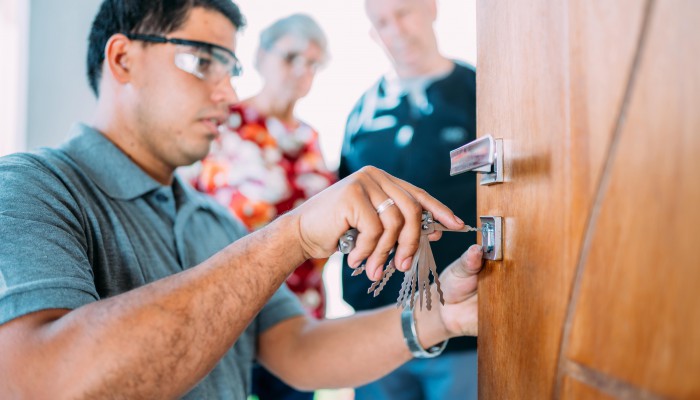 close-up-male-hands-repair-installing-metal-door-lock-senior-couple-background-min